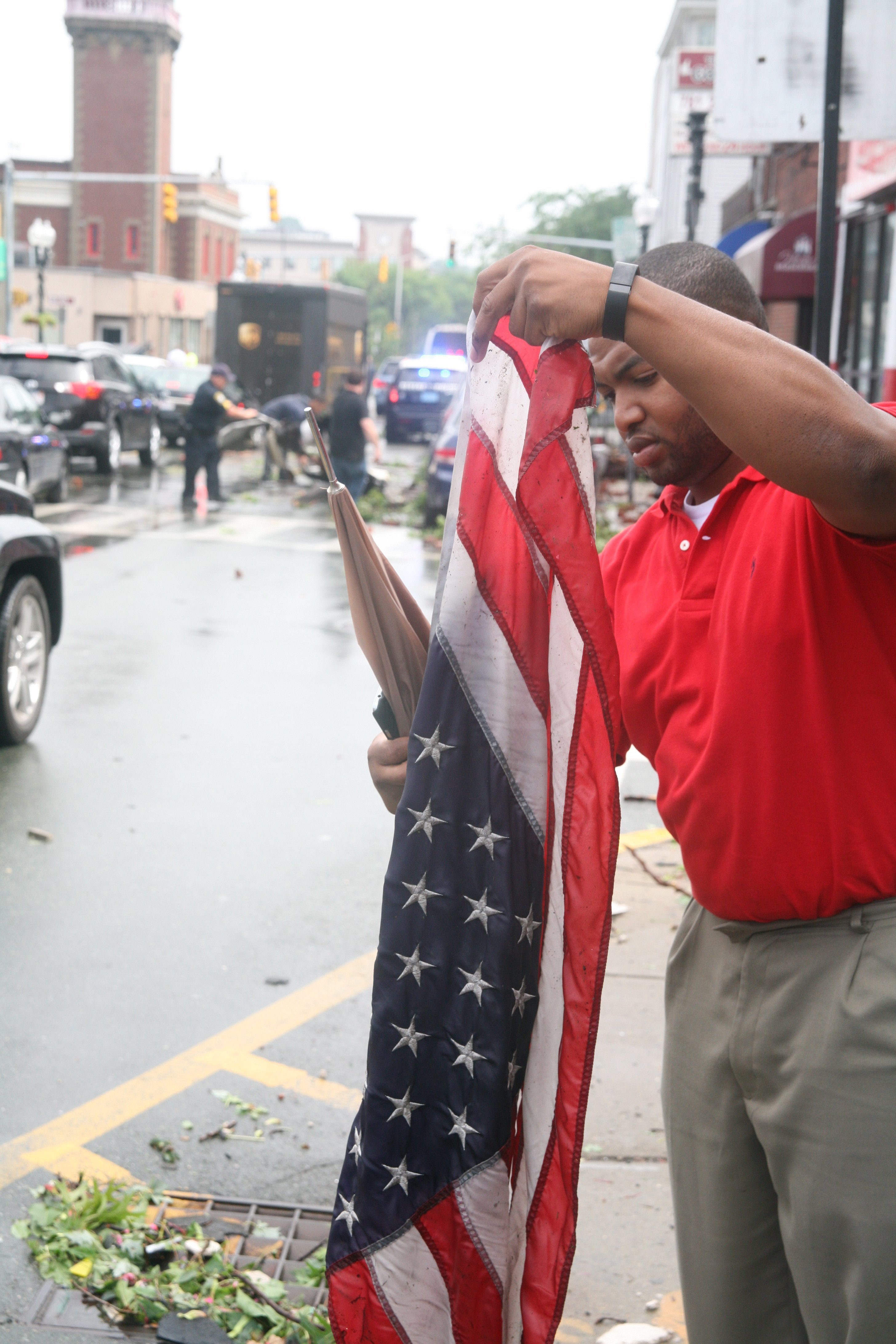 Broadway Attorney Dan Occena picks up a soiled and soaked American flag that an hour earlier hung proudly from the lightposts. Several bystanders picked up the flags out of respect from the debris in the first hour after the tornado.