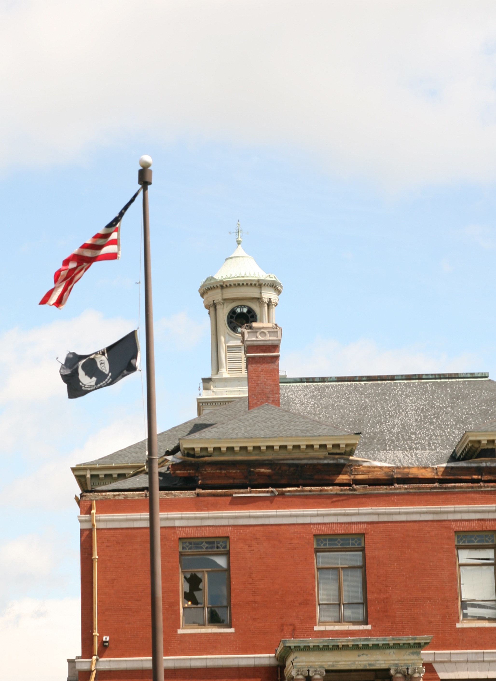 The American flag at City Hall hangs on by a thread as windows, the clock and the roof show the tremendous damage done to the Hall by the tornado. City Hall will remain closed until further notice.